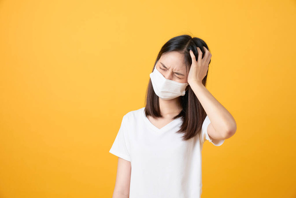 Ázsiai nők viselnek maszkot, hogy megvédje a betegség és a fejfájás egy vírus narancssárga alapon. - Fotó, kép