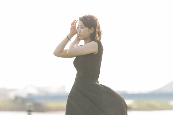 Asiatique (japonais) jeune femme en robe noire dans un parc au bord de la mer
 - Photo, image