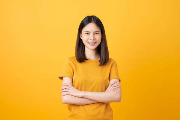 Cheerful beautiful Asian woman stand and crossed arms on orange background. - Foto, afbeelding