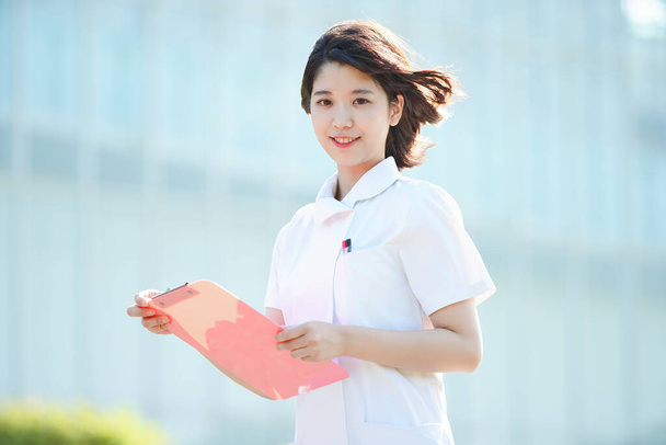 アジア人(日本人)の女性看護師が屋外で笑顔を見せる姿 - 写真・画像