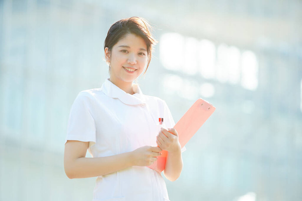 Portret azjatyckiej (japońskiej) pielęgniarki z uśmiechem na zewnątrz - Zdjęcie, obraz