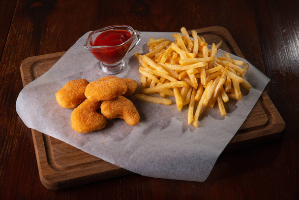 Nuggets french fries and sauce on a dark wooden background - Foto, immagini