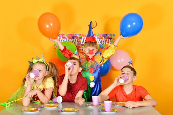 Kinder mit Clown am Festtisch feiern das Fest. - Foto, Bild