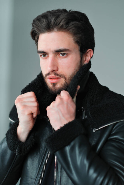 A large portrait of a stylish young man with a beard and dark hair in a black leather jacket - Valokuva, kuva