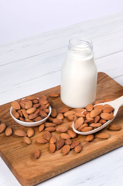 Almond milk in bottle with almond nuts on wooden background - Photo, image