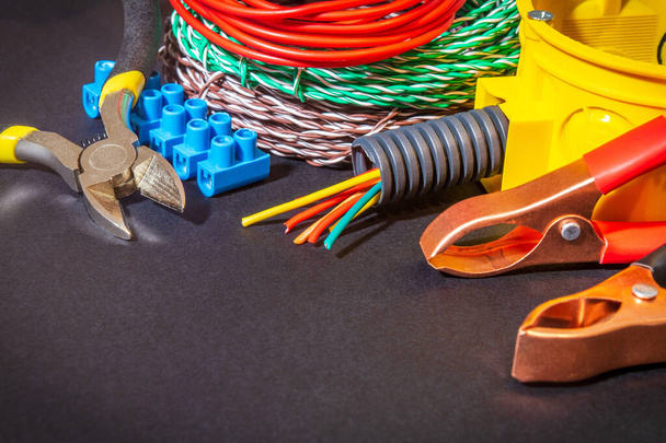 Repuestos, herramientas y alambres para la sustitución o reparación de equipos eléctricos sobre fondo oscuro
 - Foto, Imagen