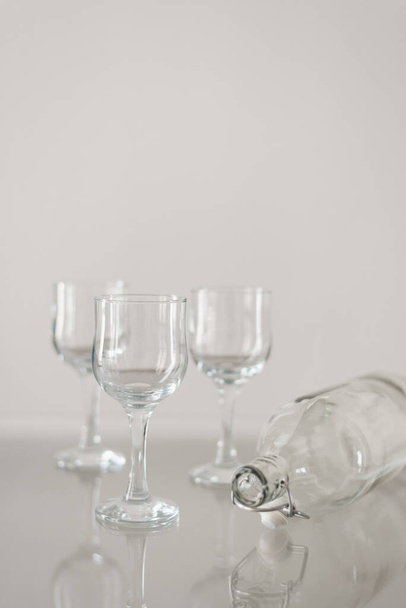 Glassware on glass table. Three wine glasses and empty bottle. Catering concept - Valokuva, kuva