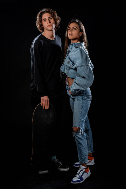 Pair of young skateboarders posing dressed in cool trendy clothing - Fotó, kép