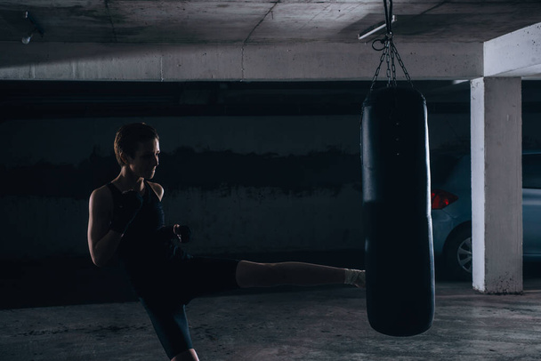 Imagen de silueta de una joven hembra pateando la bolsa de boxeo
 - Foto, Imagen