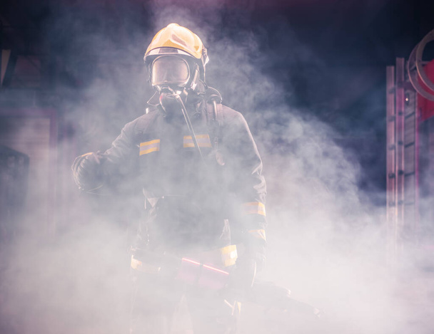 Retrato do jovem bombeiro de pé e segurando uma motosserra no meio da fumaça da motosserra - Foto, Imagem