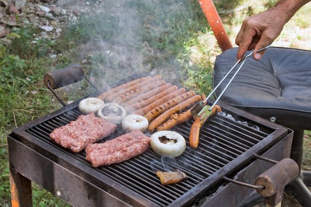 Barbecuevlees bereiden bij een picknick in de natuur. Het vlees wordt op een conventionele manier geroosterd. - Foto, afbeelding