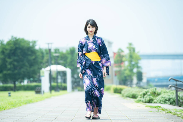 Asiática (japonesa) mujer que va a la ciudad con un yukata (traje tradicional japonés
) - Foto, imagen