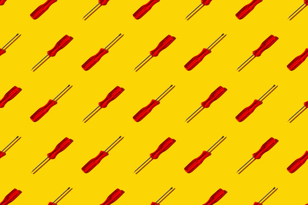 Colorful pattern of red screwdriver on yellow background. Top view. Flay lay - Fotografie, Obrázek
