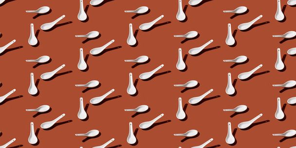 Colorful pattern of white ceramic spoon on brown background. Top view. Flay lay - Valokuva, kuva