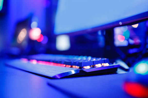 Fondo borroso jugador profesional jugando torneos juegos en línea ordenador con auriculares, rojo y azul - Foto, imagen