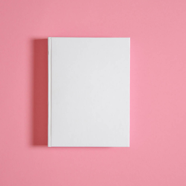 Mockup eines geschlossenen leeren quadratischen Buches auf weißem strukturiertem Papierhintergrund. Leere quadratische Buchvorlage auf hellem Hintergrund - Foto, Bild