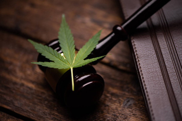 Cannabisblad en rechter hamer op houten tafel close-up - Foto, afbeelding