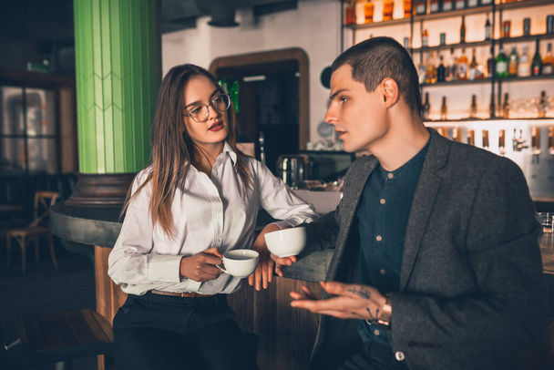 Cheerful man and woman talking, enjoying a coffee at the coffee shop, cafe, bar - Photo, image