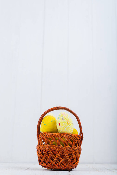 Easter decoration, pussy willow, birch leaves and yellow feather, in a white egg shell on wooden rustic background - Zdjęcie, obraz