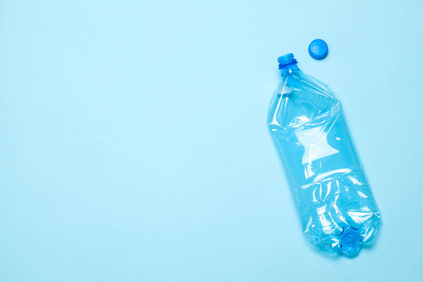 Смятые пластиковые бутылки на синем фоне. Пластиковый мусор. Копирование текста. - Фото, изображение