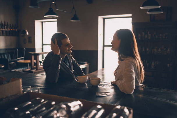 Cheerful man and woman talking, enjoying a coffee at the coffee shop, cafe, bar - Zdjęcie, obraz