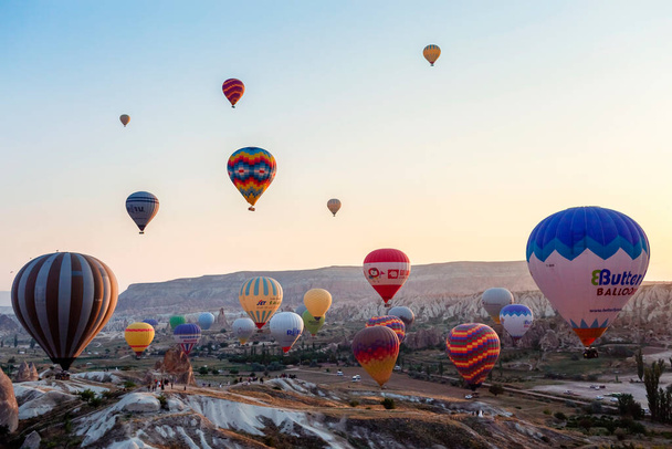 CAPPADOCIA, TURKEY  AUGUST 23, 2019:flight of hot air balloons at sunrise in Cappadocia. Goreme, Cappadocia, Turkey. Moment of balloons landing - 写真・画像