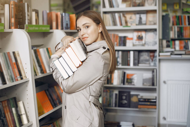 Student looking for a book in the library - Фото, изображение