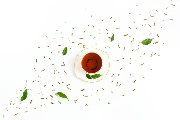 Copa de cerámica de té elaborado, hojas verdes frescas y hierbas secas dispersas sobre fondo blanco. Concepto de ceremonia del té matutino. Composición plana. Diseño creativo
. - Foto, imagen