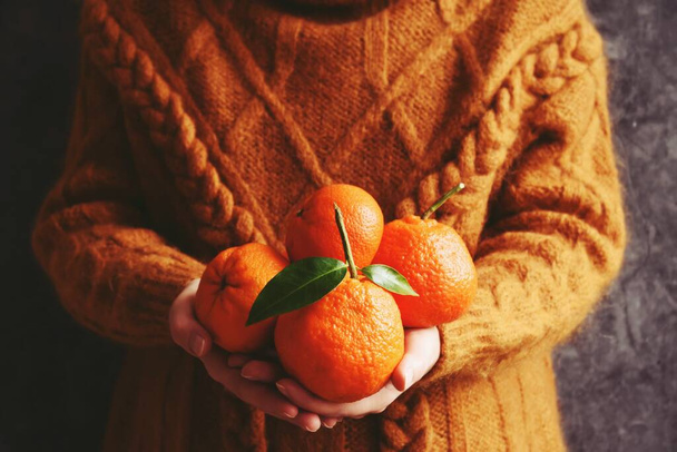 kobieta w swetrze z pomarańczami w rękach, widok przycięty  - Zdjęcie, obraz