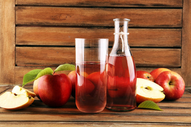 Bebida de cidra de maçã e maçãs com folhas na mesa rústica
 - Foto, Imagem