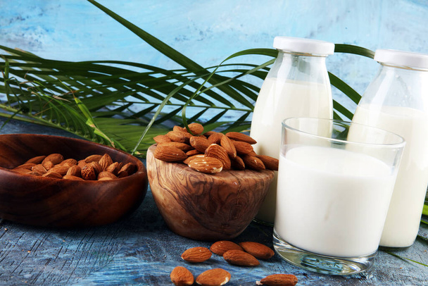 мигдальне молоко зі свіжими горіхами та листям пальми на фоні. мигдальний веганський молочний
 - Фото, зображення