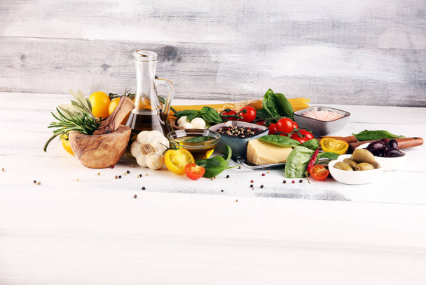 Italian food background with herbs and spices, vine tomatoes, basil, spaghetti, olives, parmesan, olive oil, garlic, peppercorns and rosemary - Photo, Image