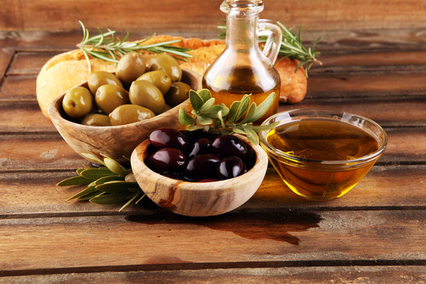 Fles vergine olijfolie en olie in een kom met olijven. - Foto, afbeelding