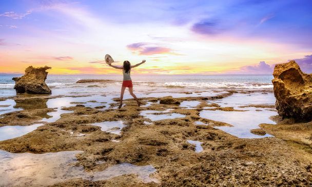 若い女性の観光客は、日没時にニール島の岩のビーチでエクスタシーでジャンプします。写真撮影:自然橋ニール島｜アンダマン・インディア.  - 写真・画像