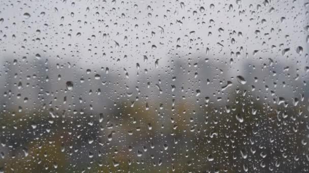 Dešťové kapky na okno. Oknem stékají kapky deště. Kapky vody nebo kapky deště kapky na okenní sklo s rozmazanými budovami pozadí. Smutek, touha, otupělost, podzimní deprese, chmury. - Záběry, video