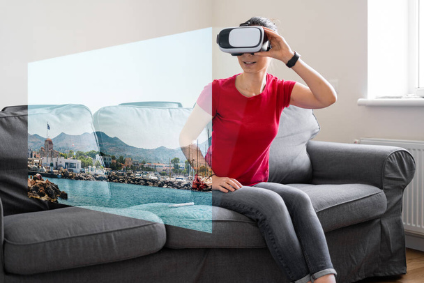Woman with VR glasses sitting on the sofa at home and watching online travel photo. VR booking, getting experiences - Valokuva, kuva