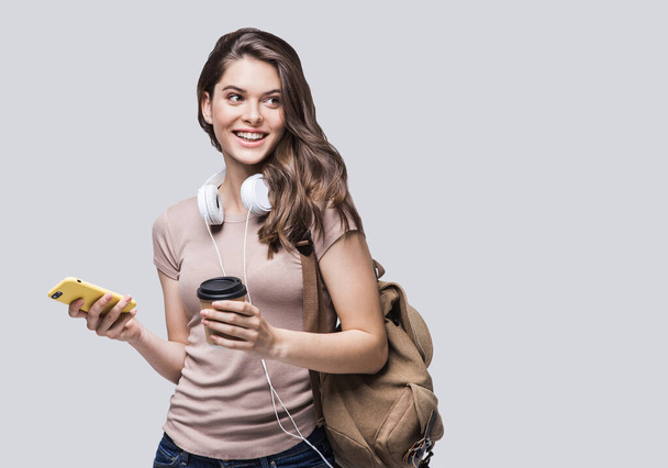 Young beautiful student girl with smart phone and rucksack - Φωτογραφία, εικόνα