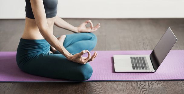 Young woman practicing yoga at home. Online video training. Girl doing exercises and meditate. Yoga, balance, meditation, relaxation, healthy lifestyle, online training class concept. - Photo, Image