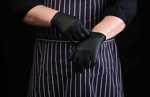 chef hombre en uniforme negro y vestidos de delantal rayado guantes de látex negro, de bajo perfil
 - Foto, Imagen