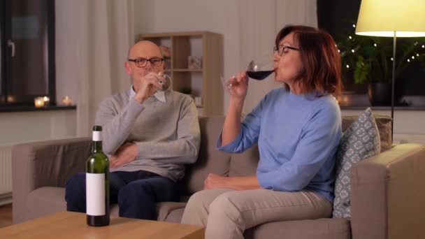 šťastný starší pár pije červené víno doma - Záběry, video