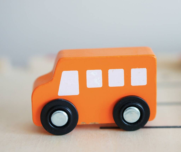 A closeup shot of an orange miniature wooden toy car - Фото, изображение