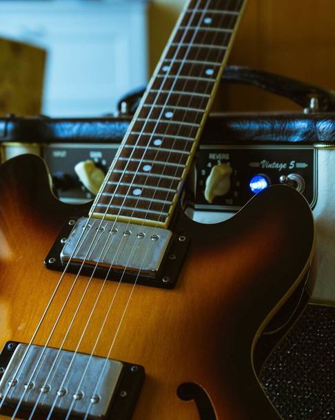 A closeup vertical shot of a brown electronic guitar - 写真・画像
