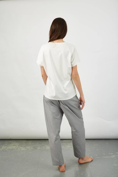 A vertical shot of the back of a brunette female in a white shirt and grey trousers - Фото, зображення
