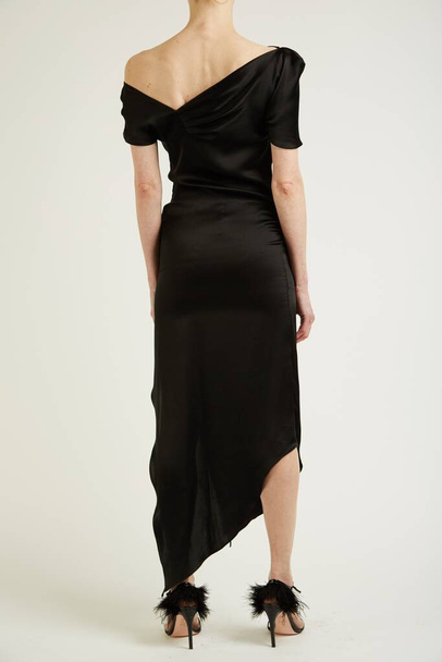 A vertical shot of a female model wearing a black long dress and black high heels - Valokuva, kuva