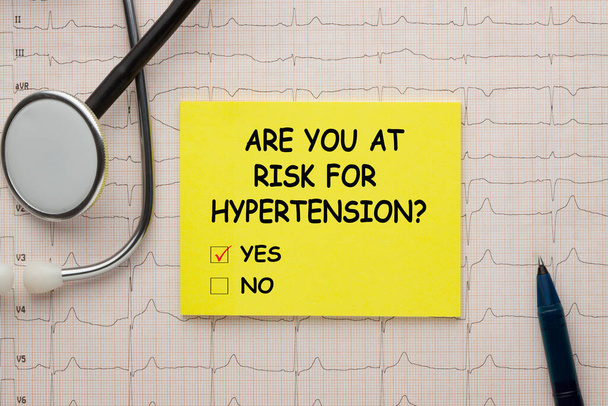 Bent u in gevaar voor hypertensie vraag ja of nee tekst op toon met stethoscoop en hartslag, cardiogram en EKG concept. - Foto, afbeelding