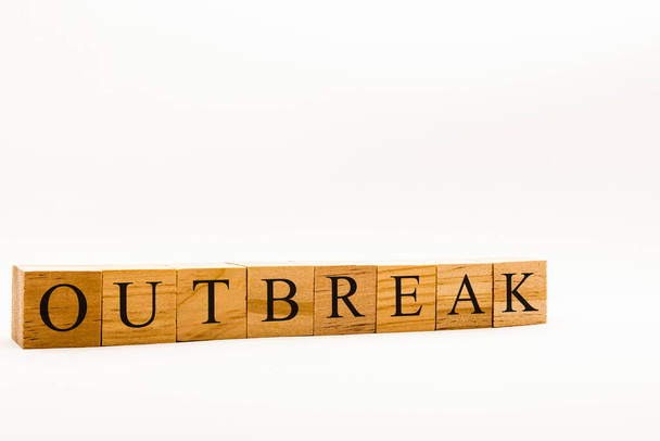 Coronavirus concept showing wooden blocks on a white background reading Outbreak - Фото, изображение