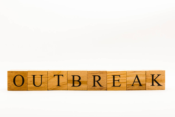 Coronavirus-Konzept zeigt Holzklötze auf weißem Hintergrund mit der Aufschrift Outbreak - Foto, Bild
