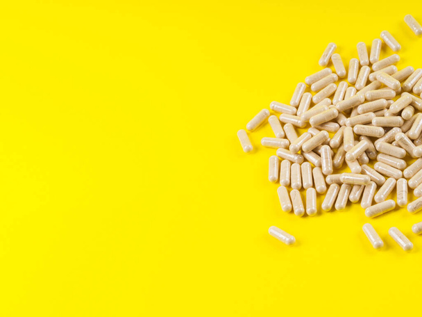 Maca powder in capsules on yellow background - Photo, Image