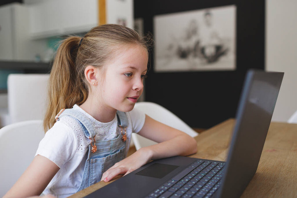 girl working on her laptop during home schooling during corona crisis - 写真・画像
