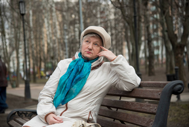 An elegantly dressed old woman is sitting on a bench in an alley in the Park . Active longevity. - Foto, immagini